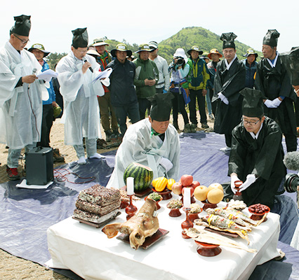 한복을 입은사람들이 제를 지내는 모습과 그뒤로 관람하는 사람들의 모습